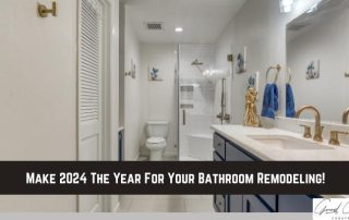 Modern bathroom with white walls, blue cabinets, double sink, glass shower, and a toilet; text overlay reads, “Make 2024 The Year For Your Bathroom Remodeling!”.