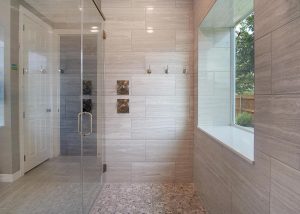Modern bathroom with glass shower enclosure, large window, built-in bathtub, tiled walls, and pebble stone shower floor.