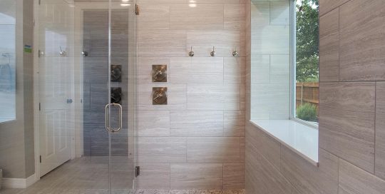 Modern bathroom with glass shower enclosure, large window, built-in bathtub, tiled walls, and pebble stone shower floor.